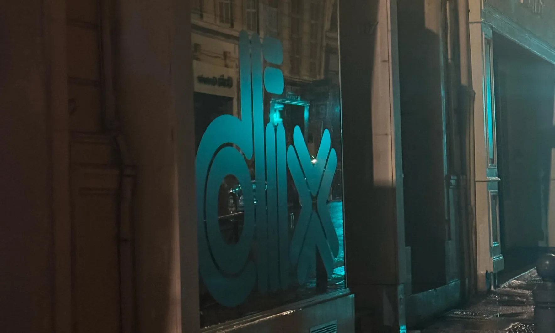 Le mot « dix » en adhésif bleu sur la vitrine de Jogging, de nuit, rue Paradis. Image de l'article « Jogging – 10 ans ».
