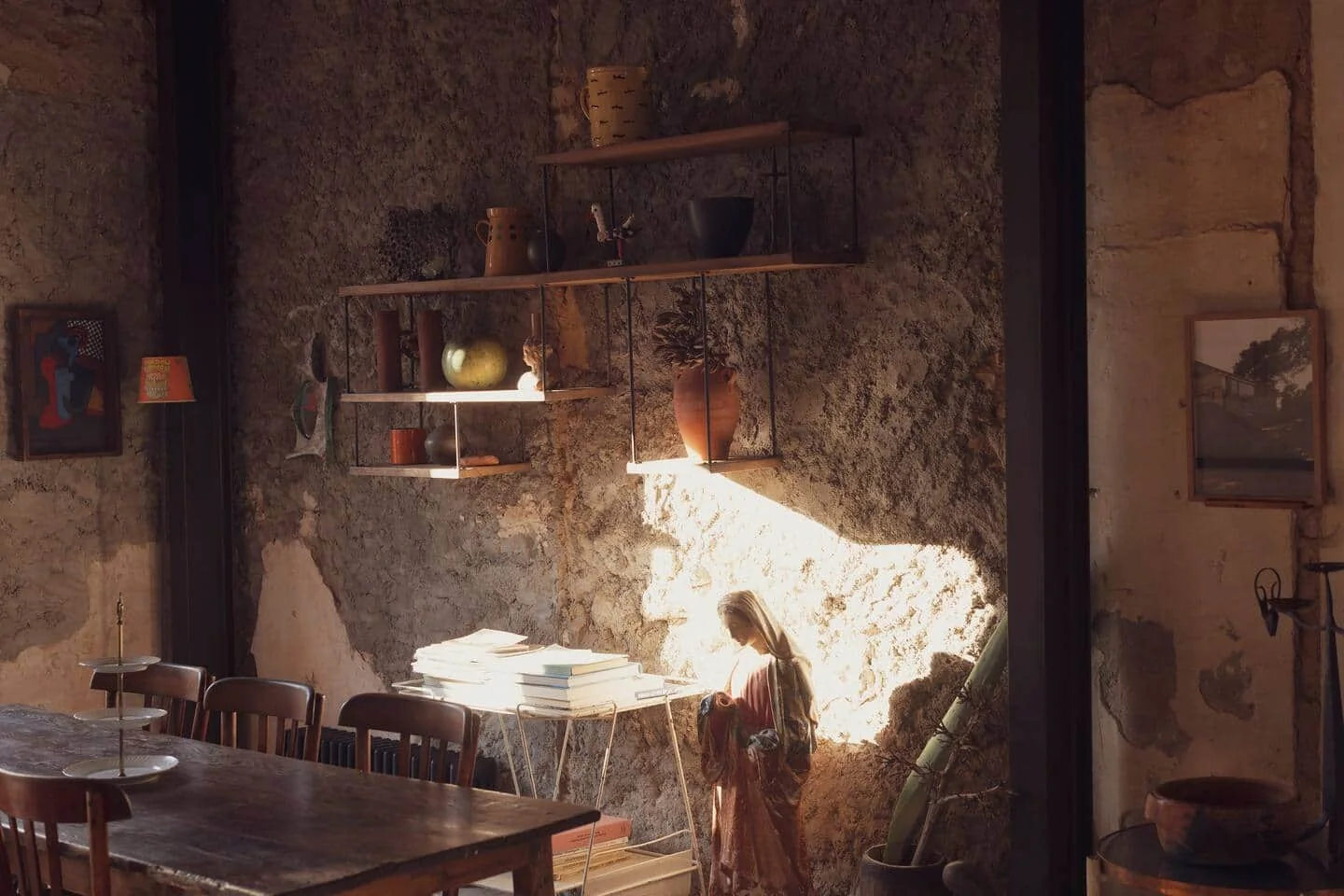 Samena : une salle aux murs de pierre, une lumière rasante sur les tables et les chaises.