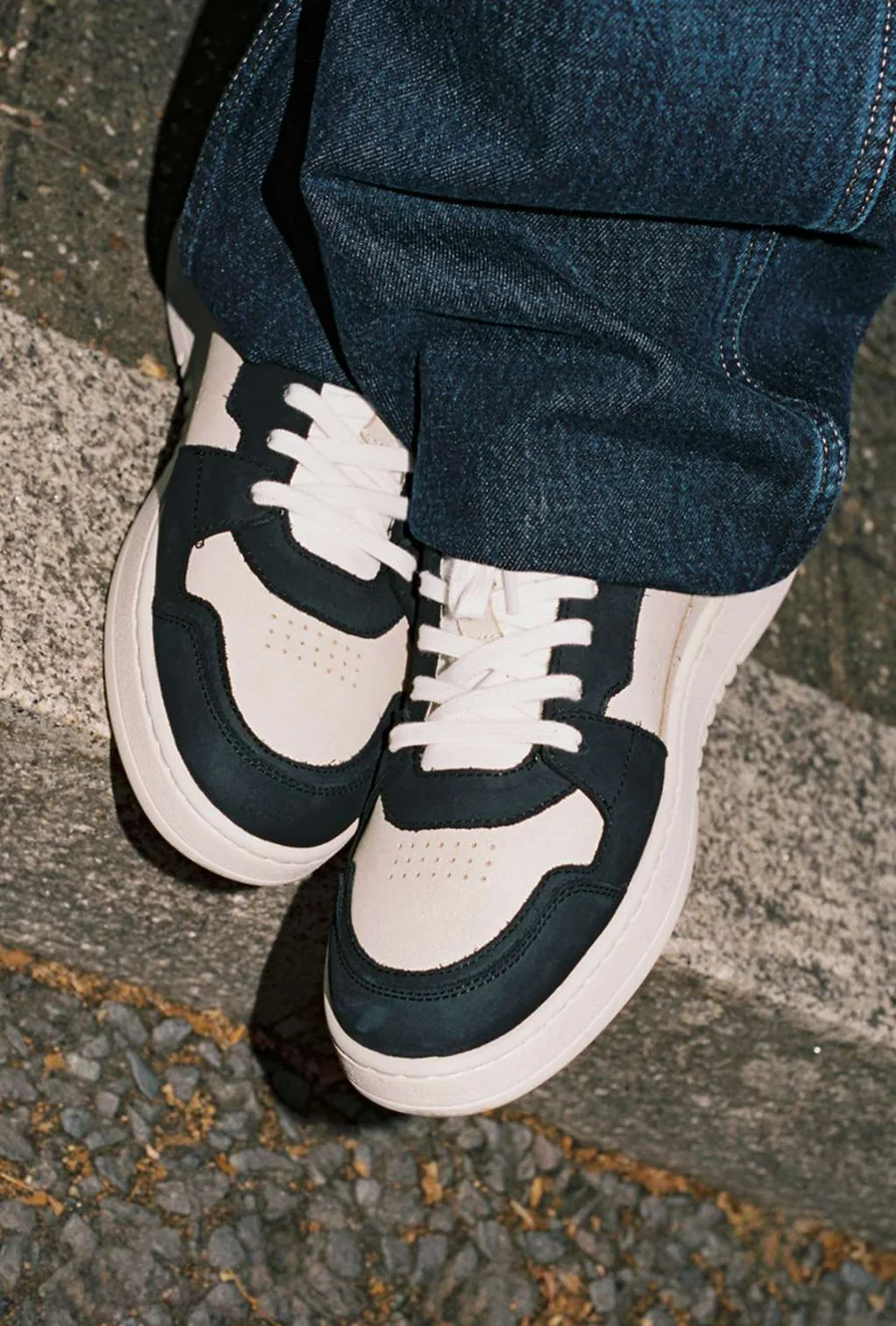 Sneaker Axel Arigato portée, photographiée sur des pavés.